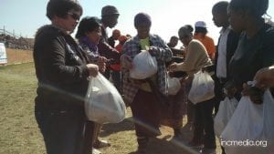People receiving relief goods in white plastic bags