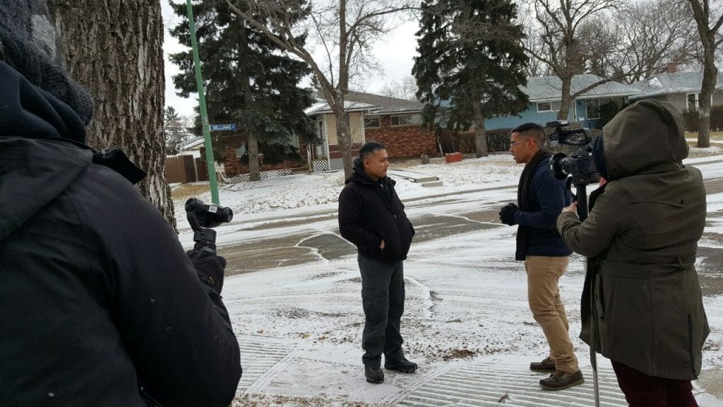 Nan Zapanta interviewing Mike Bigayan outside in the snow with 2 camera men recording them.