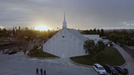 Birds eye view of the exterior of the house of worship with the sunset in the background.
