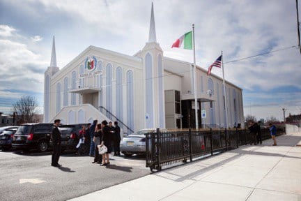 Exterior of Jersey City house of worship with a group of people standing outside on a clear day.