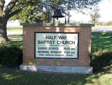 A park setting with brick wall signage that reads Half Way Baptist
Church