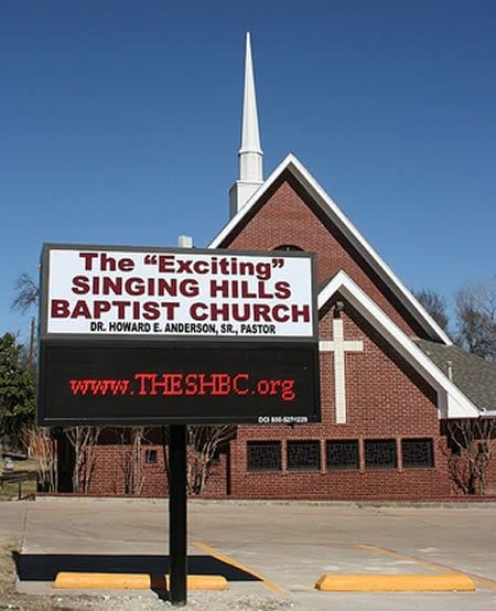 A sign in front of a chapel that says The “Exciting” Singing Hills Baptist
Church