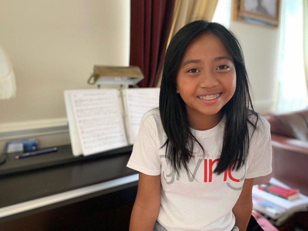 Girl with INC Giving Tshirt with Piano in Background.