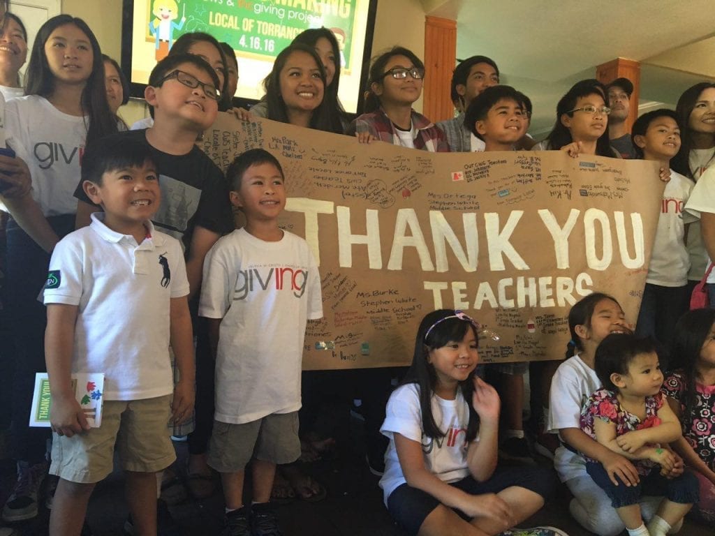 Young INC Giving Volunteers with a thank you sign for teacher appreciation day.