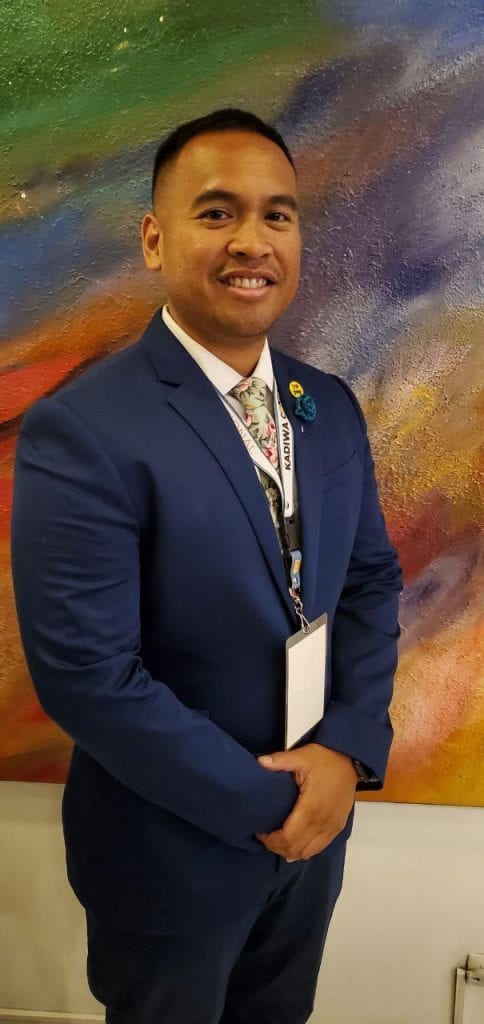 Michael Kani Rivera in a blue suit in front of a painting