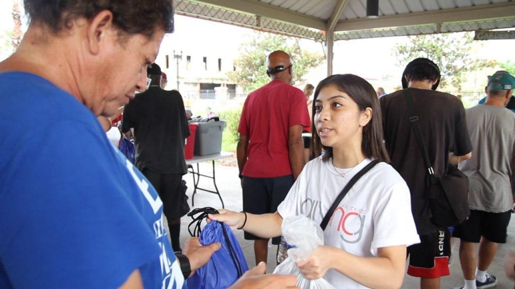 INC Giving Volunteer handing goods to community member in need.