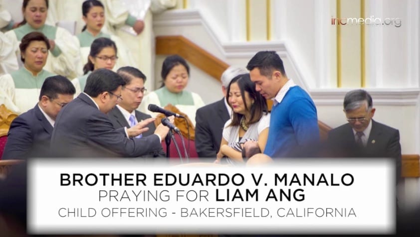 A couple holds their newborn son who is being prayed over by the Executive Minister. 