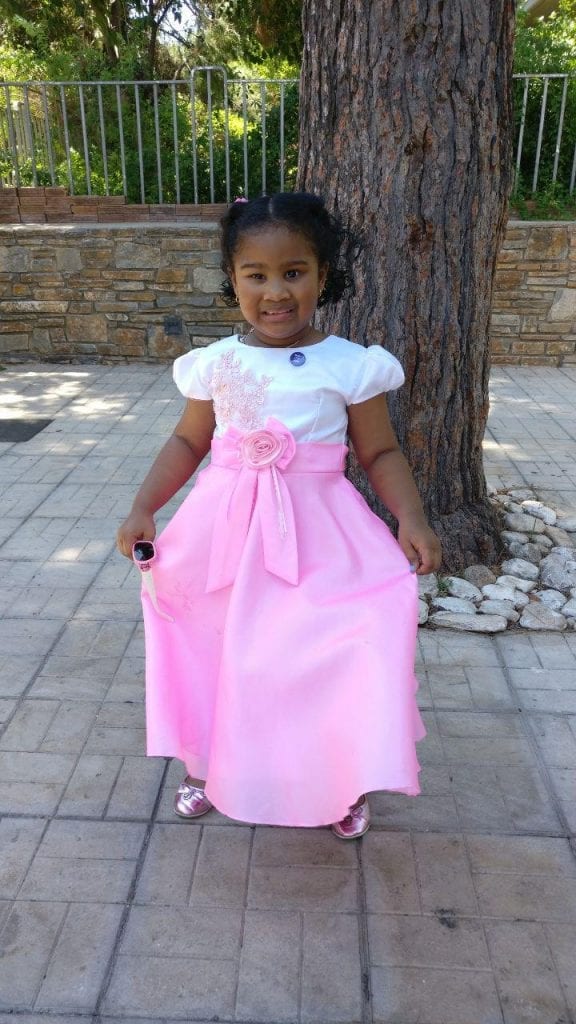 A girl in a pink and white dress showing off her fancy clothes. 