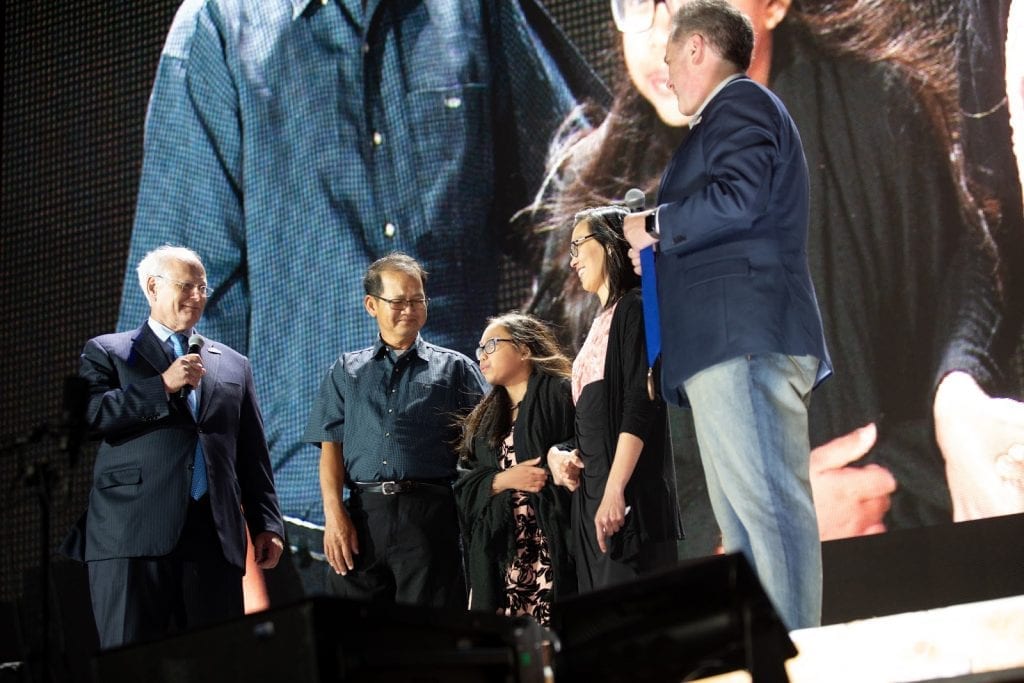 A group of five individuals on stage with a jumbotron behind them projecting their image. 