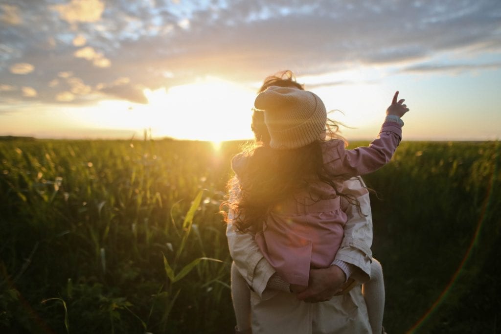 Woman carrying a little girl in the field.