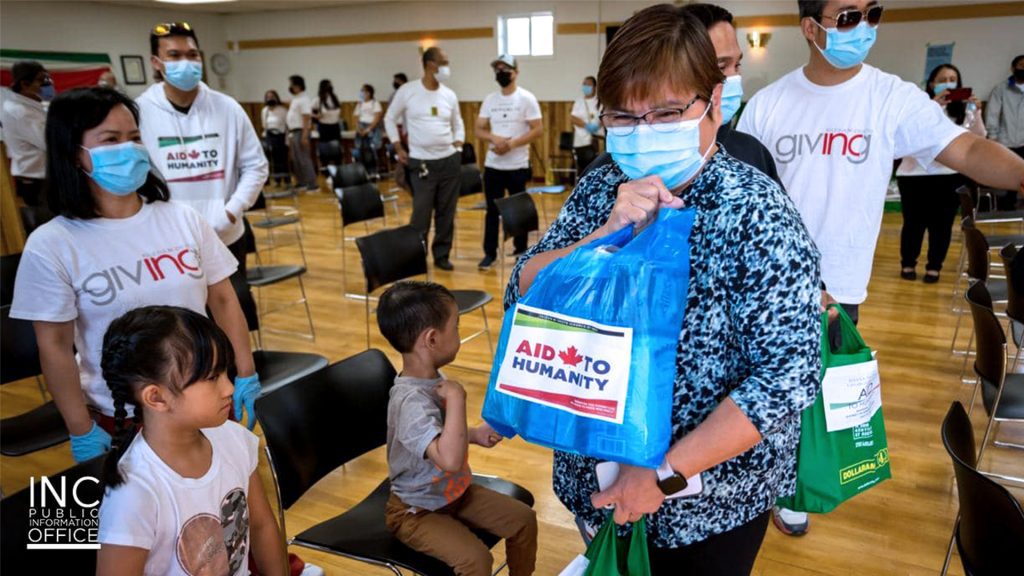 An excited lady from the town of manning holding a bag of non-perishable food with it labeled “Aid to Humanity”