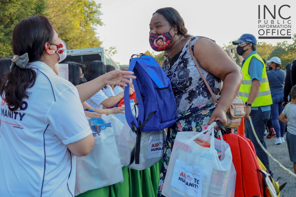 An Aid to Humanity attendee receives a care package of food items and a book bag of school supplies.