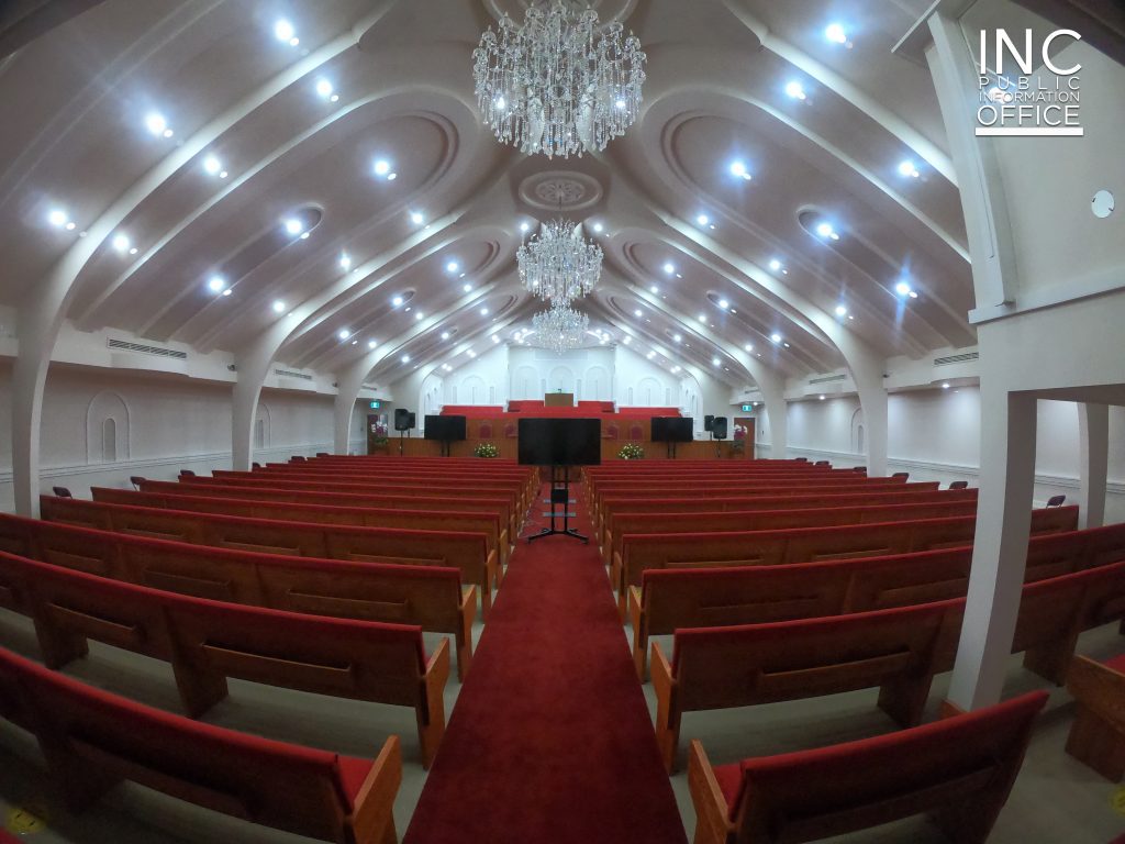 The interior of a Church Of Christ or Iglesia Ni Cristo (INC) chapel with new chandeliers and lights, bright white millwork on ceiling, refurbished pews, and a new organ.