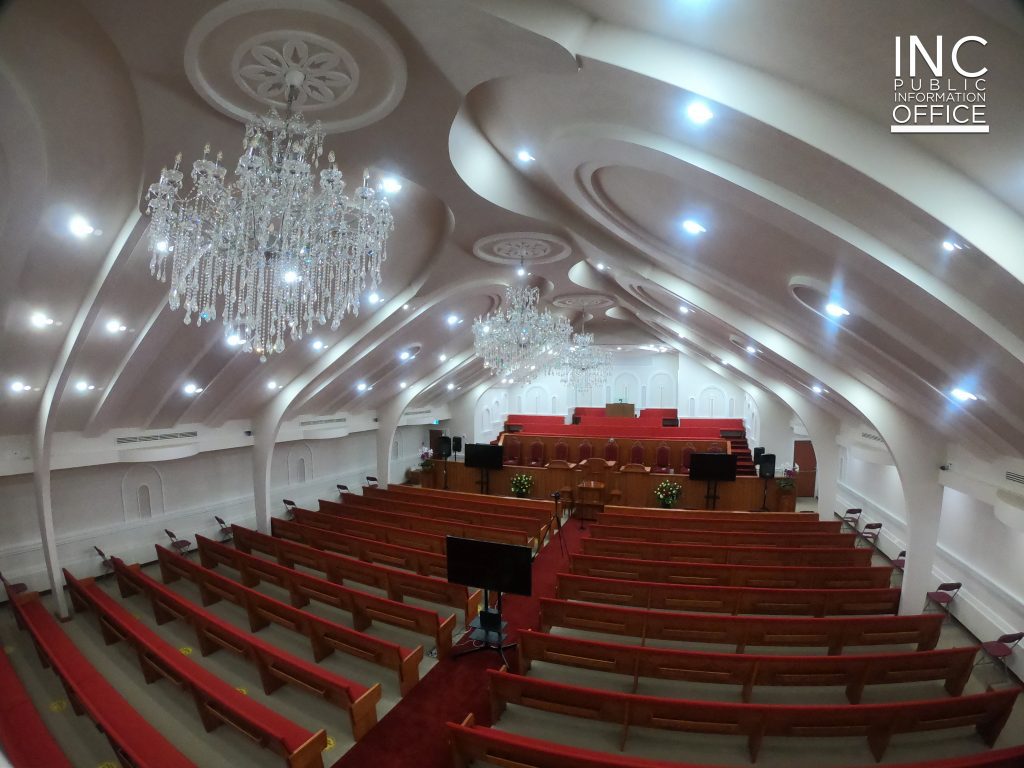The interior of a Church Of Christ or Iglesia Ni Cristo (INC) chapel with new chandeliers and lights, bright white millwork on ceiling, refurbished pews, and a new organ.