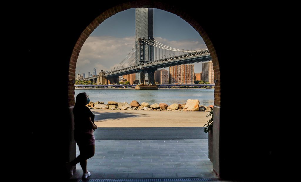 woman standing in an arch with a bridge in the background