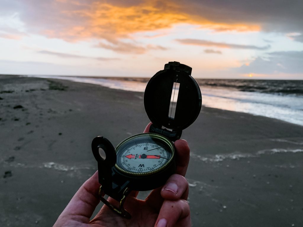 hand holding a compass on the beach