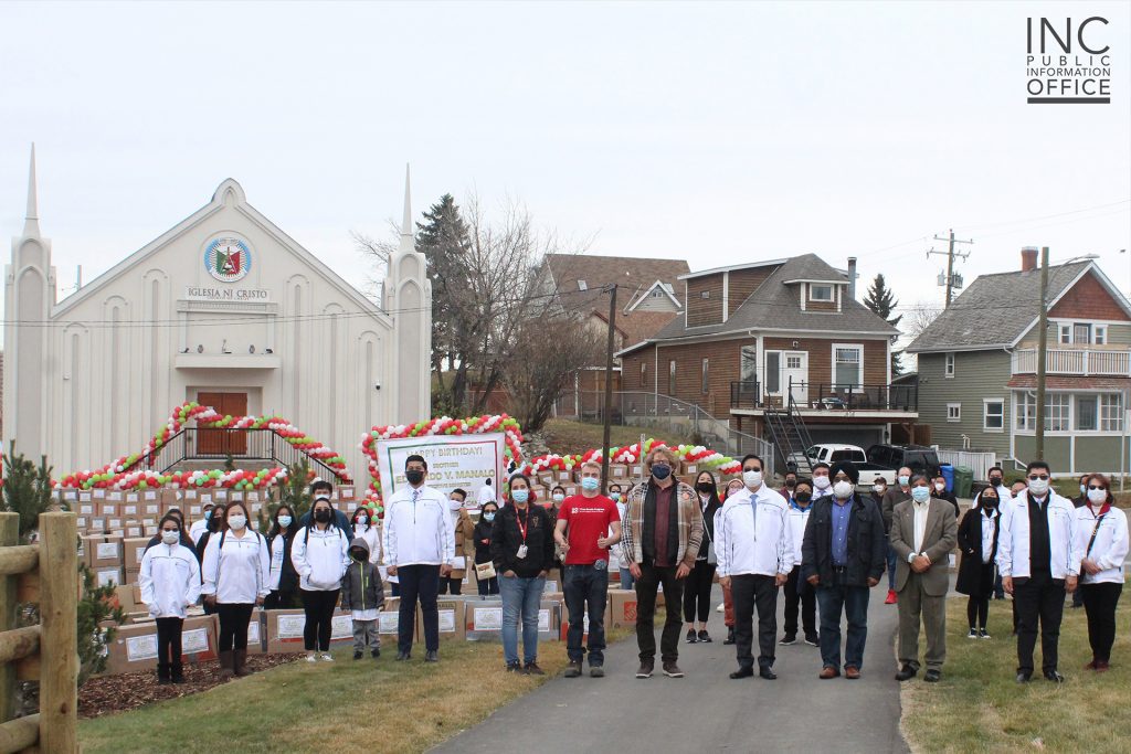 INC ministers and members pose for a group photo, along with Gian-Carlo Carra and Devinder Toor, with the Downtown congregation’s house of worship in the background.