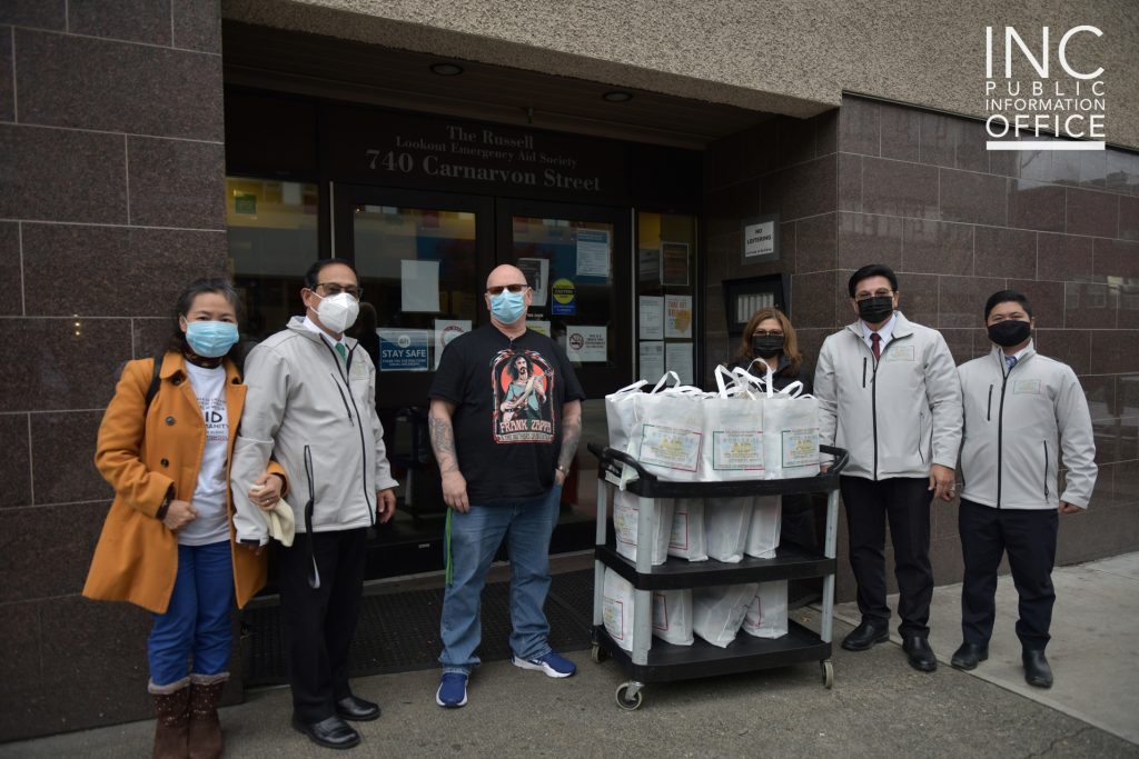 A representative of the Russell shelter stands with Church Of Christ members at the entrance to the building with the bags of donated care packages on a cart.