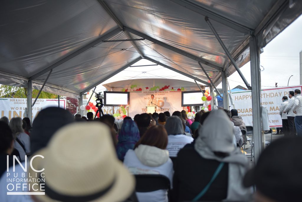 Guests and representatives from the recipient organizations gather with Church Of Christ members in a tent on the Surrey chapel grounds to watch a brief program.