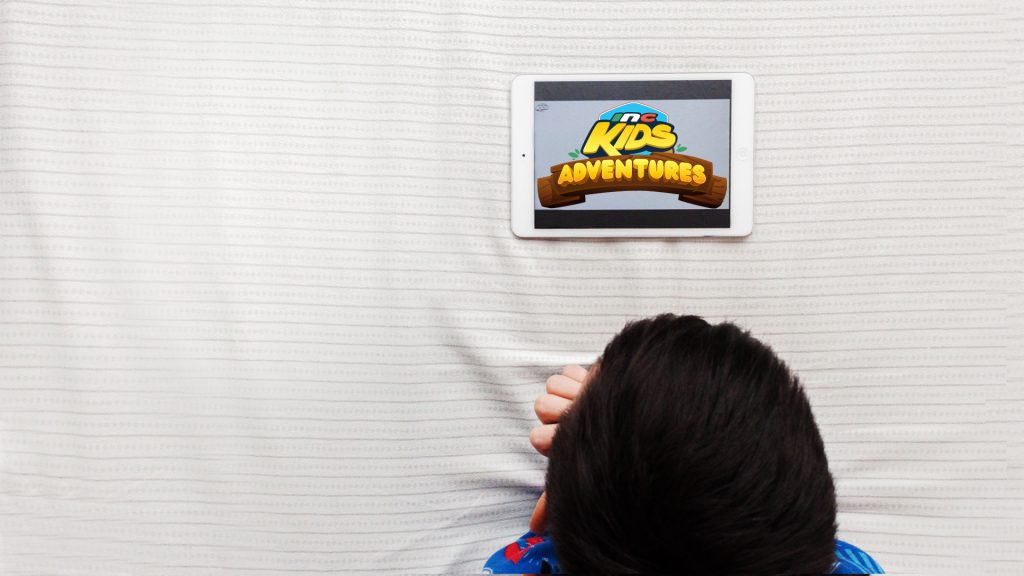 Top of little boy’s head while watching inckids adventures on tablet