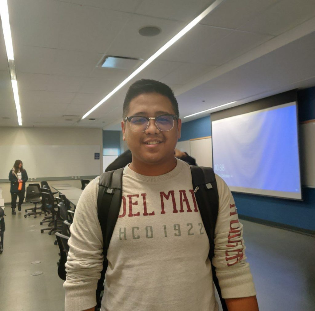 a man with a backpack and a screen behind him