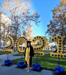 college student in front of 2021 sign made of balloons